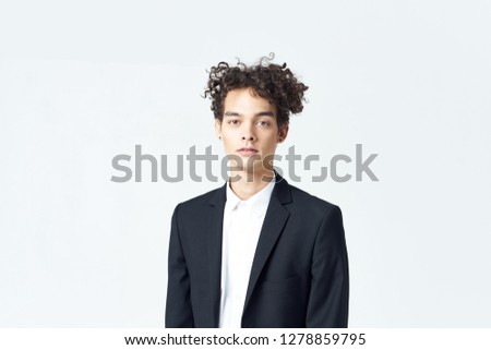 Business man with curly hair in a black jacket on a light background              