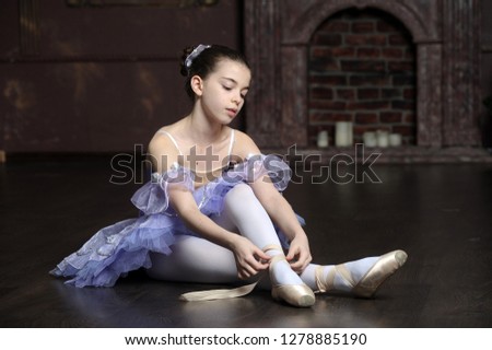 Little ballet dancer putting on pointes.