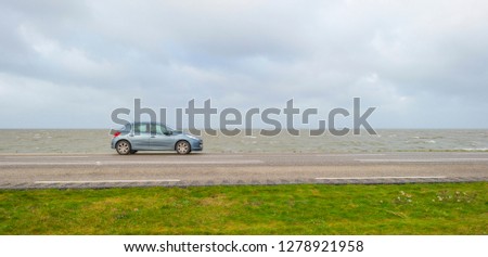 Car parked on a dike along a lake in winter