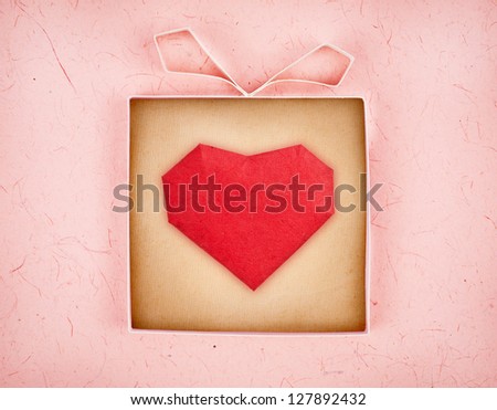 Hand made gift box with heart inside, textured  paper as background. Greeting card