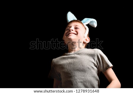 Funny happy blond boy in his ears ears bounces on a black background