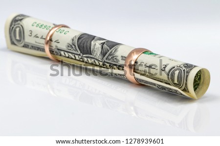 One-dollar bill rolled into a tube and threaded into a gold ring