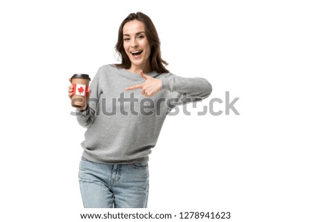 smiling woman pointing with finger at coffee cup with canadian flag sticker isolated on white