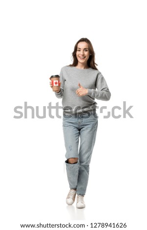 woman showing thumb up sign and holding coffee cup with canadian flag sticker isolated on white
