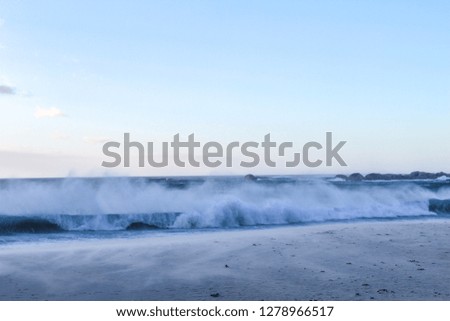 Scenic landscape picture of waves crashing on the beach on a summer evening at Camps bay in Cape Town, South Africa