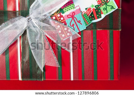 Shiny ribbon knot on red striped Christmas gift box.