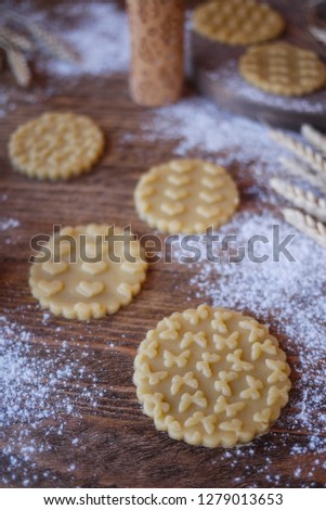 Cutting cookies with a print of butterflies and hearts on a wooden table. Wooden rolling pins in the picture