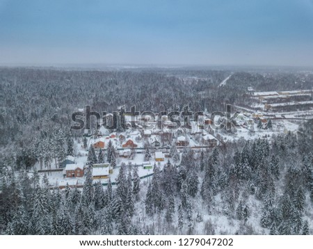Little village in the forest, aerial view. Beautiful winter landscape.  Aerial drone photo, top down, of suburban houses in Moscow region, Russia, everything is white and covered by snow. 
