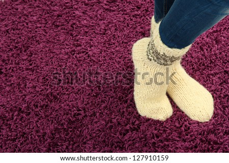 Female legs in colorful socks on color carpet background