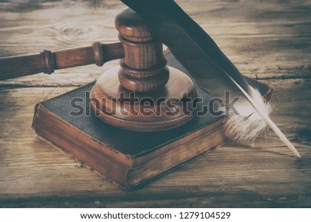 Law gavel or judge mallet and feather pen on a wooden desk