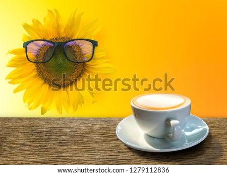 A cup of hot coffee  placed on a wooden table .And sunflower on orange design background  with copy space for your message. Coffee time concept in the morning