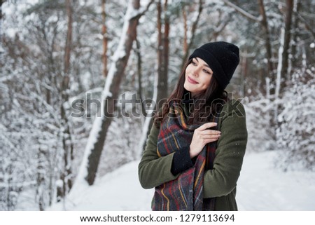 Feeling joy. Cheerful young girl in warm clothes have a walk in the winter forest at daytime.