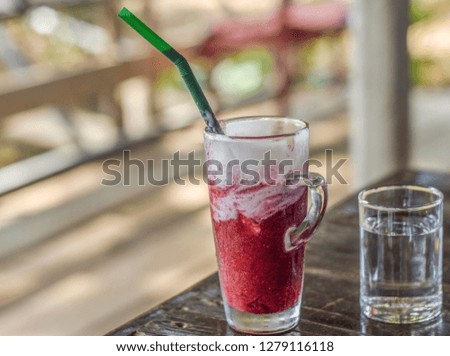 Glass of healthy red cold drinks mixed berry smoothie with cream on steel grating bar.