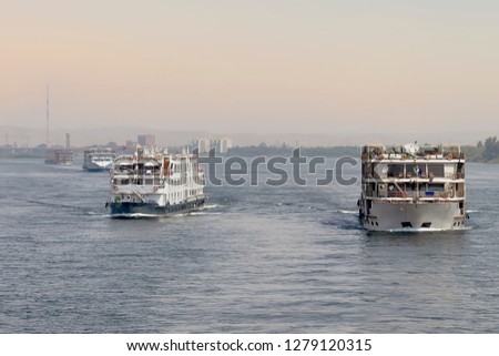 Tourist boats on the Nile river. A fleet of floating hotels (tourist boats) motor down the River Nile towards Aswan in central Egypt. The tourist boats cruise between Luxor and Aswan in Upper Egypt
