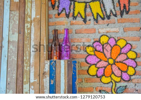 flower candel on brick wall and colour bottle on the wood wall