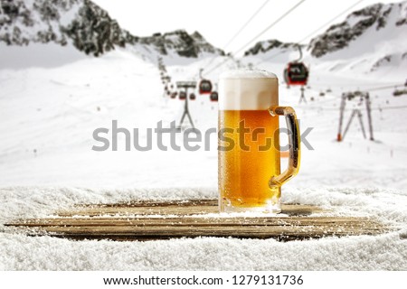 Winter time in Alps and beer in glass with free space for your bottle 