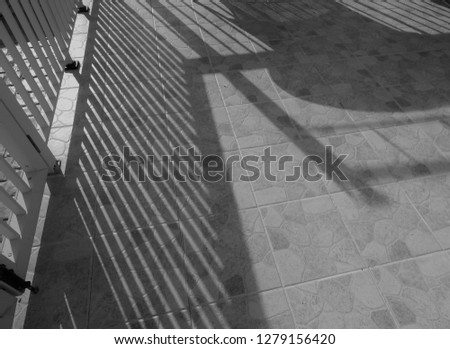 Shadows created by railings playing across a tiled patio