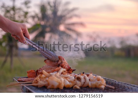 Someone grilling food on the barbecue grills in the garden. Royalty-Free Stock Photo #1279156519