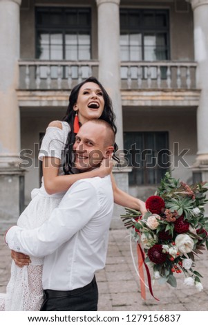 Charming and stylish wedding couple poses before a building of an old castle