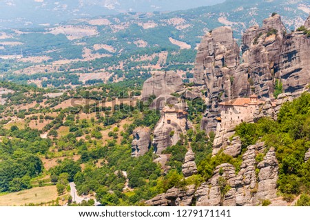 Meteora, Greece - June 16, 2013: Panoramic view on scenic Meteora landscape rock formations with Saint Nicholas of Anapafsas monastery on the cliff and mountains range and valleys on the background