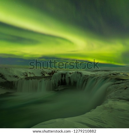 A stunning aurora  above the landscape of Godafoss water fall in winter Iceland. Green northern lights. Starry sky with polar lights. Most popular place in iceland. Tourism