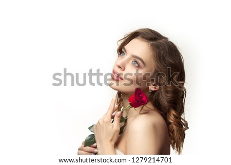 Nice young smiling woman with long wavy silky hair, natural make up looking at camera with red rose isolated on white background. Model with fresh shiny skin and natural make-up. People emotions