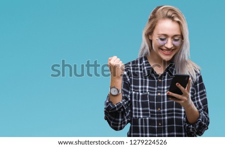 Young blonde woman texting sending message using smartphone over isolated background screaming proud and celebrating victory and success very excited, cheering emotion