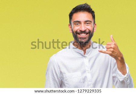 Adult hispanic man over isolated background smiling doing phone gesture with hand and fingers like talking on the telephone. Communicating concepts.