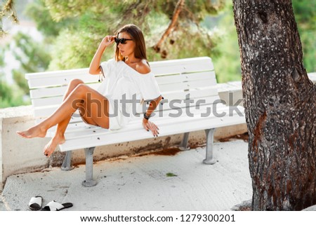 
Beautiful urban woman in white dress sitting on the bench and  enjoy the life.