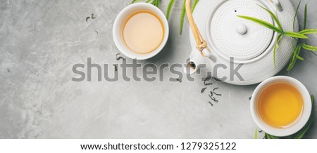 Asian food background set with green tea, cups and teapot with liefs and free space for text on grey concrete background. Flat lay. Long wide banner Royalty-Free Stock Photo #1279325122