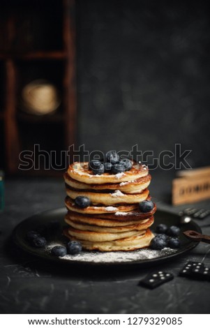 Tasty breakfast. Lush homemade pancakes sprinkled with powdered sugar with fresh blueberries. On a wooden background.