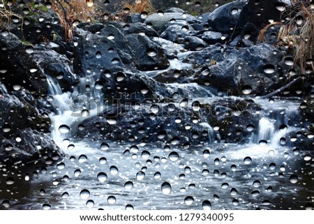 View of the stream through the window glass covered by raindrops 