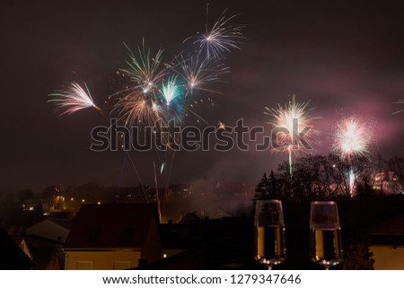 color picture with fireworks over Mainz, Germany, two champagne glasses blurred in front
