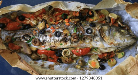baked fish sea bass in parchment paper with vegetables, spices and herbs