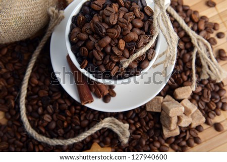Roasted coffee beans with cup on jute hessian background