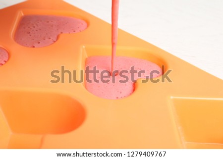 Pouring smoothie into ice cube tray on table, closeup