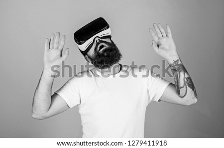 Man with beard in VR glasses. Hipster on busy face exploring virtual reality with modern gadget. VR gadget concept. Man wearing virtual reality goggles. Studio shot, grey background.