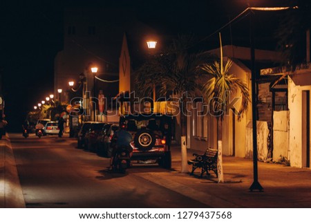 Night street of a small coastal Mexican city. Parked cars, shop windows, bars. Cozumel Island. Mexico