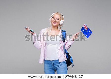Smart young blond woman in headphones satisfied with learning language during online courses using smartphone, smiling female student doing homework task, searching information via mobile phone