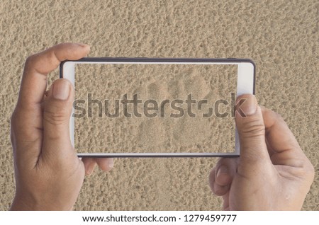 Mobile phones take pictures of dog paws printed on the sand.