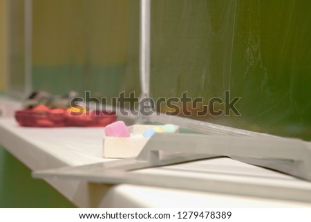 chalk, ruler, protractor, triangle on a stand under the blackboard in the classroom
