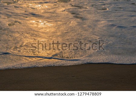 The letter X created by ocean wave foam during golden sunrise on the beach in Duck, North Carolina.  