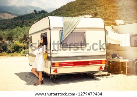 Beautiful young woman outside the camper van on a summer day beach mountains in background, Albania