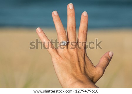 Photo of woman's hand with engagement ring at the beach.  