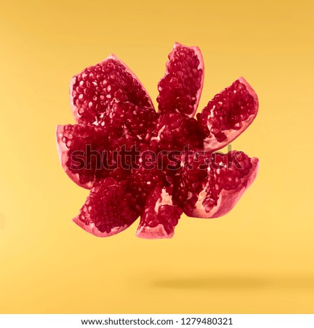 Flying in air fresh ripe pomegranate isolated on yellow background. High resolution image
