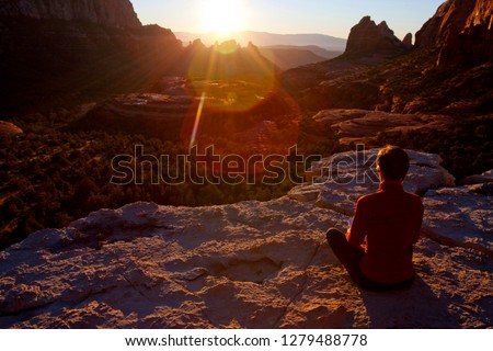 Woman alone sitting outdoors on a rocky ledge at sunset in Sedona Arizona Royalty-Free Stock Photo #1279488778