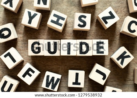 Letter block in word guide with another block on wood background