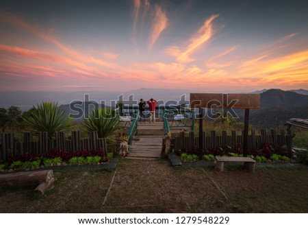 Young Asian men take pictures in the sunset view point of Doi Ang KhangCamping site in Doi Ang Khang ,Chiang Mai Thailand