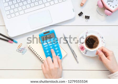 Female hands working on calculator. Office desktop on white background.