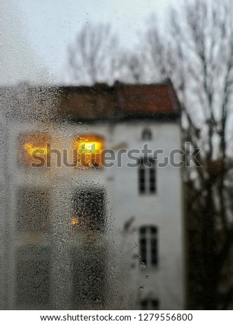 raindrops over the first half of the window with lights in the background of the building